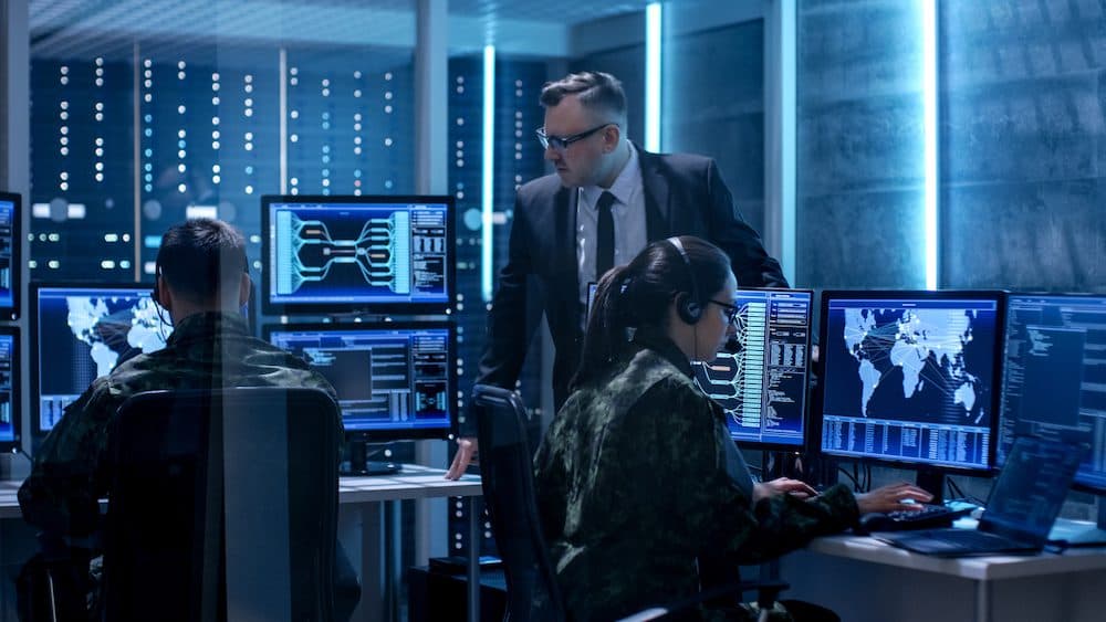 Team of Government Agents Tracking Fugitive with Boss's Survillance in Big Monitoring Room Full of Computers with Animated Screens. (Team of Government Agents Tracking Fugitive with Boss's Survillance in Big Monitoring Room Full of Computers with Anim