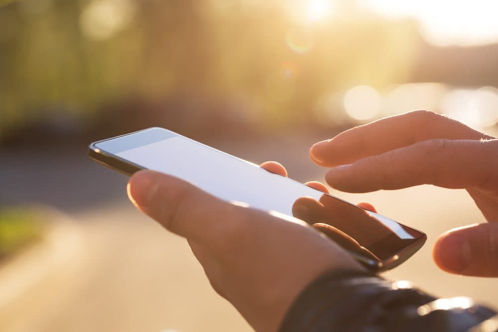 Man using his Mobile Phone outdoor, close up
