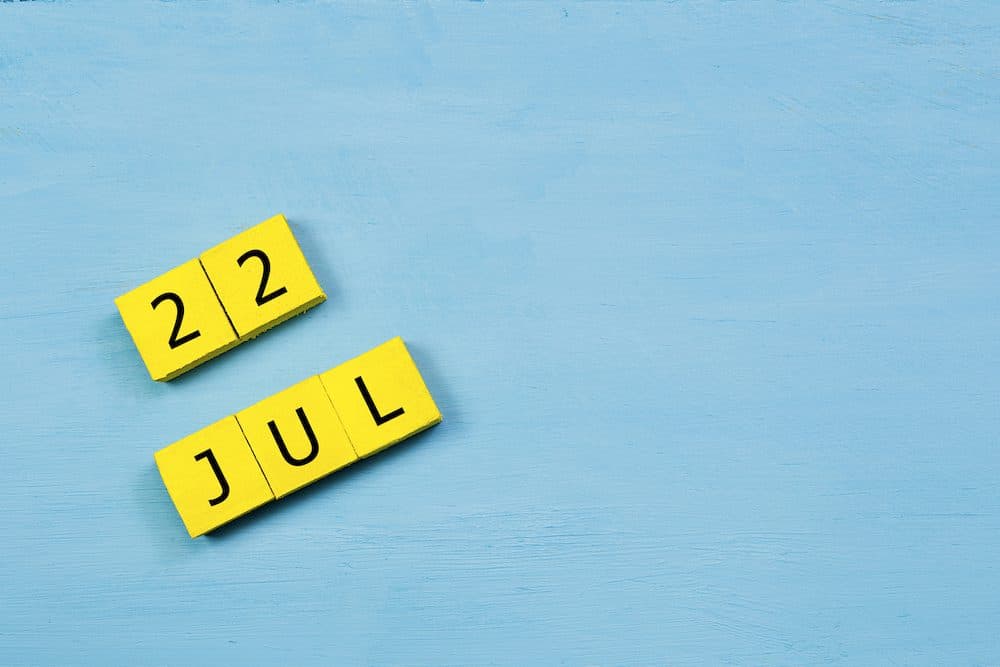 JUL 22, yellow cube calendar on blue wooden surface with copy space