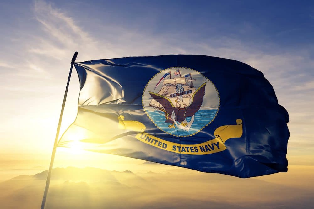 United States Navy flag on flagpole textile cloth fabric waving on the top sunrise mist fog