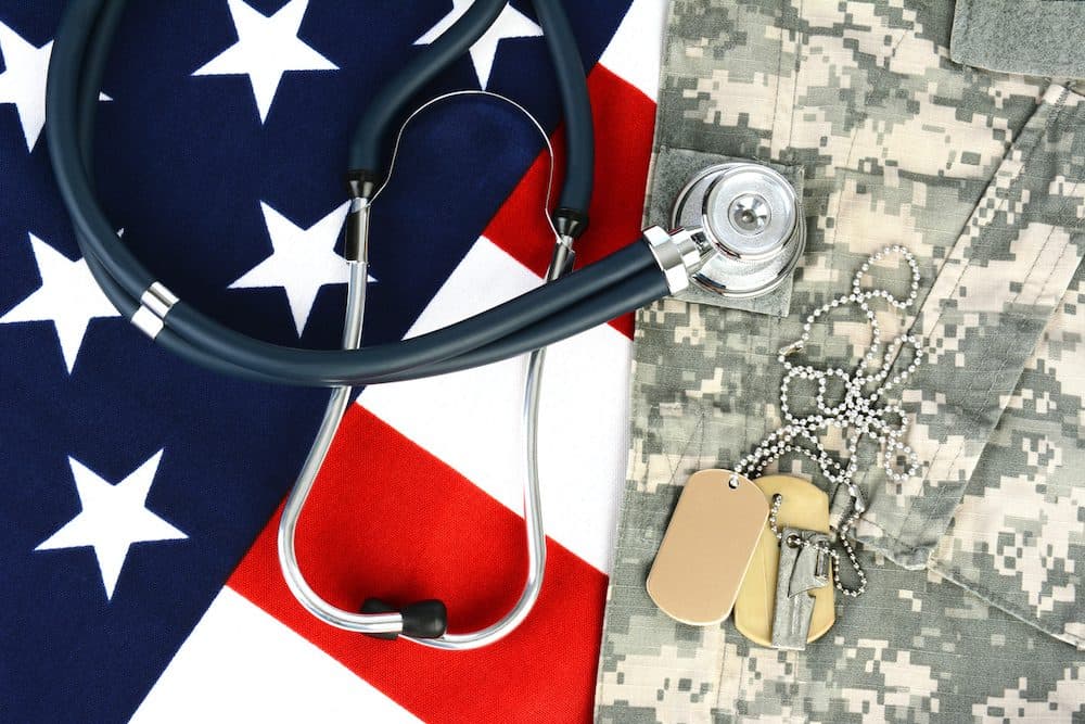 Military fatigues and dog tags on an American Flag with a stethoscope to illustrate health care in the armed services. Horizontal format, fills the frame. (Military fatigues and dog tags on an American Flag with a stethoscope to illustrate health care