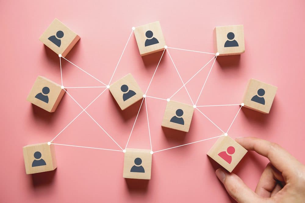 Building a strong team, Wooden blocks with people icon on pink background, Human resources and management concept.