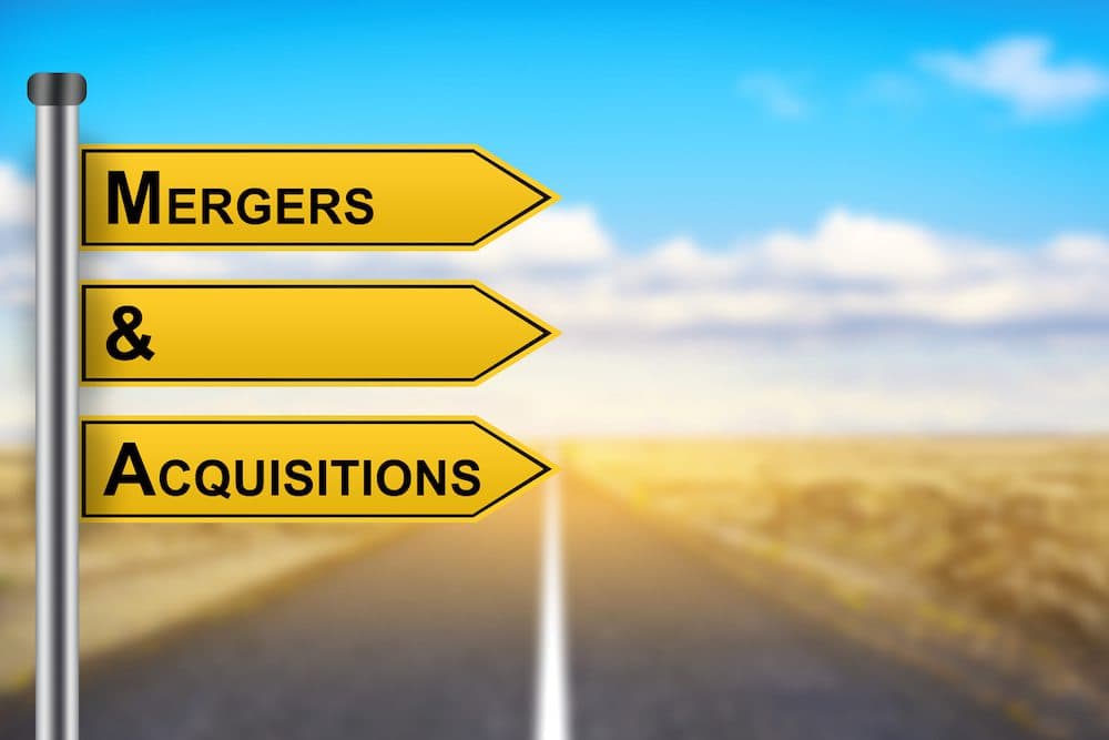 M&A or Mergers and Acquisitions words on yellow road sign with blurred background