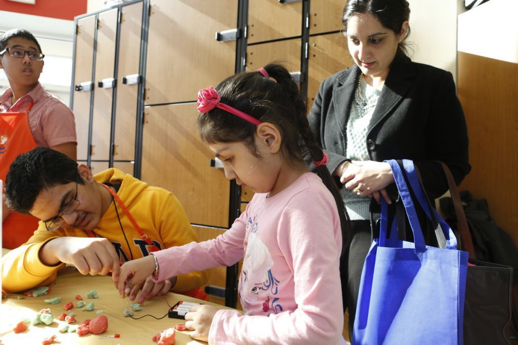 Virginia Run Elementary School student Bonnie Gill, 5, tries a science experiment with the help of Ishaan Lubana of the Children's Science Center while her mother Sheena Gill looks on.