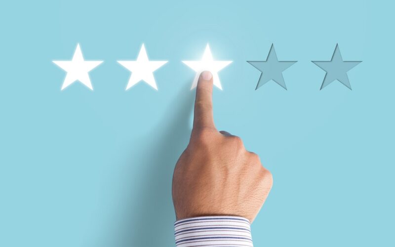 Hand choosing 3 stars rating on blue background - Average feedback on blue background