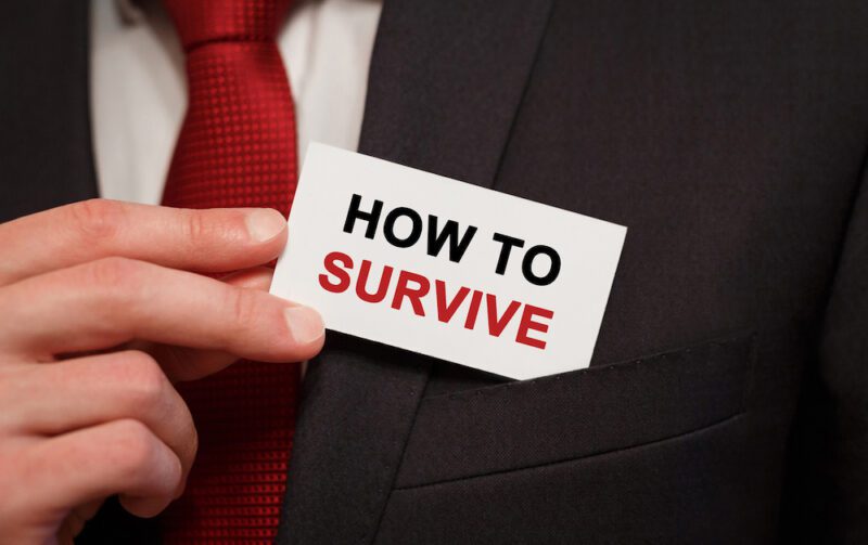 Businessman putting a card with text How to survive in the pocket