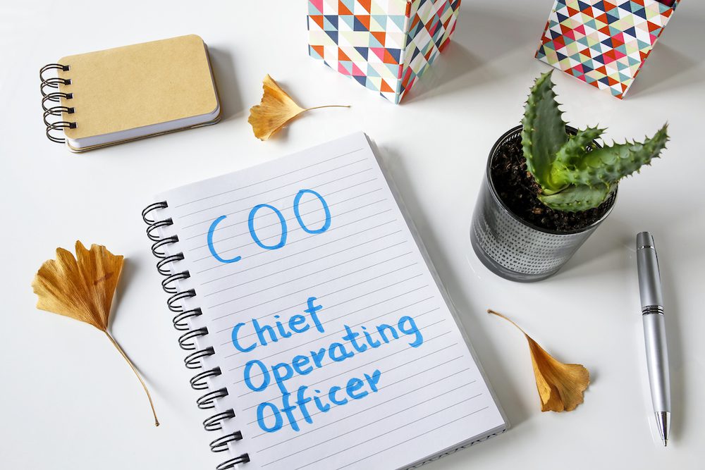 COO- Chief Operating Officer written in a notebook on white table