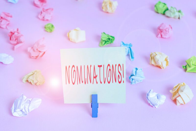 Writing note showing Nominations. Business concept for action of nominating or state being nominated for prize Colored crumpled papers empty reminder pink floor background clothespin (Writing note showing Nominations. Business concept for action of no